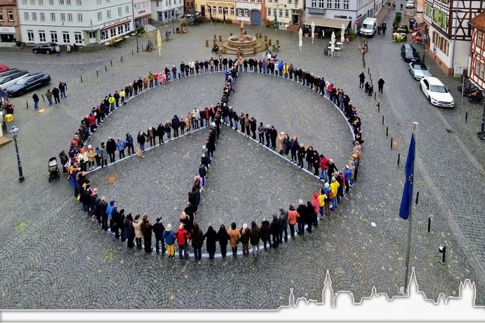 Die Teilnehmer der Friedenskundgebung stellen sich auf dem Markplatz im Form des Friedenszeichens auf.